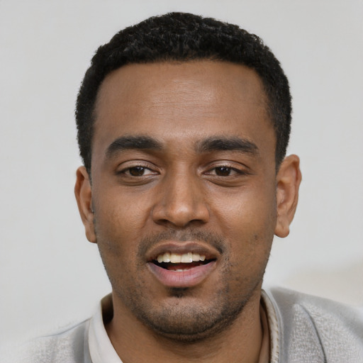 Joyful black young-adult male with short  black hair and brown eyes