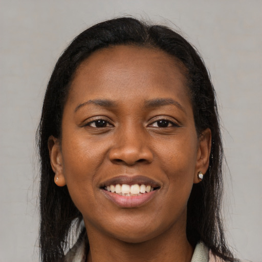 Joyful black young-adult female with long  brown hair and brown eyes