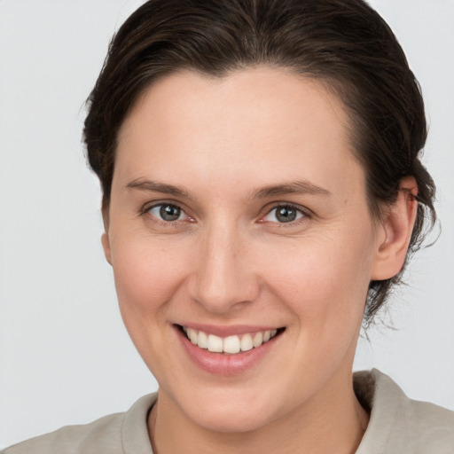 Joyful white young-adult female with medium  brown hair and grey eyes