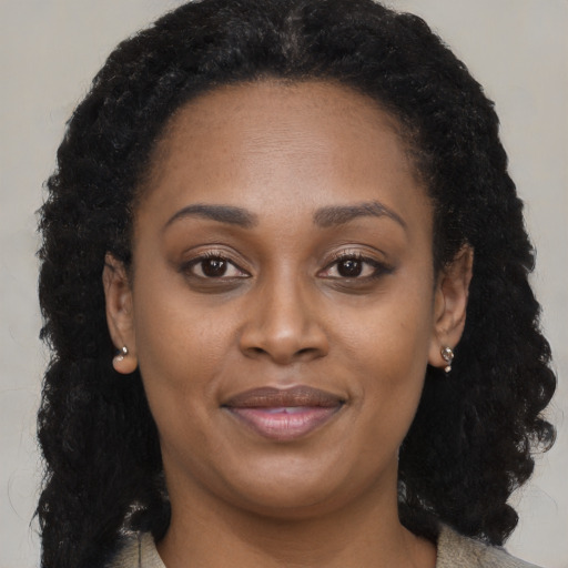 Joyful black young-adult female with long  brown hair and brown eyes