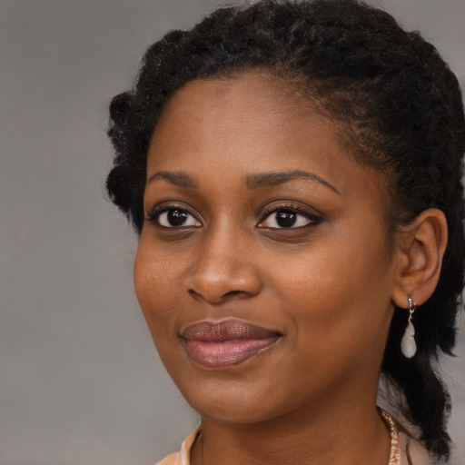Joyful black young-adult female with long  black hair and brown eyes