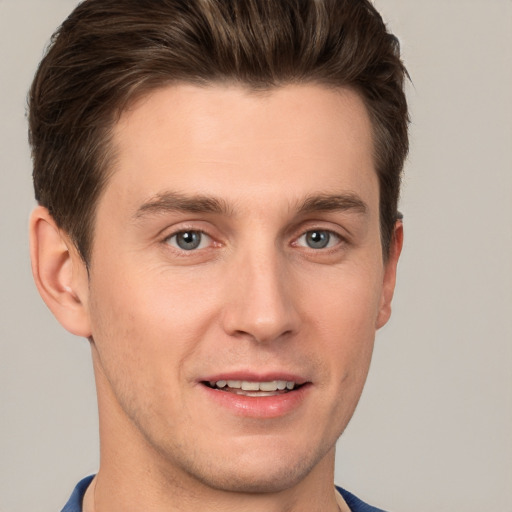 Joyful white young-adult male with short  brown hair and grey eyes