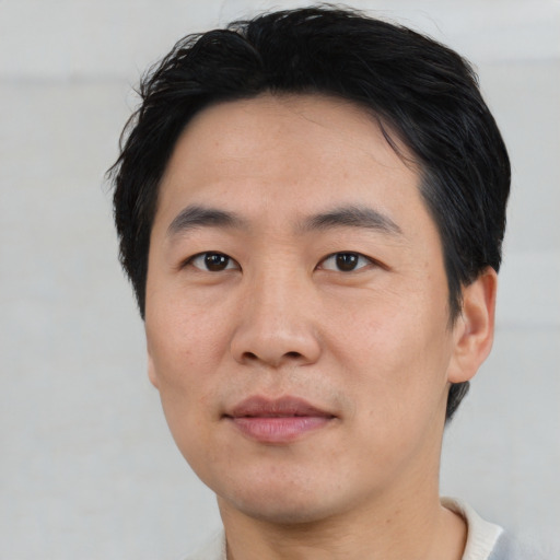 Joyful asian young-adult male with short  black hair and brown eyes