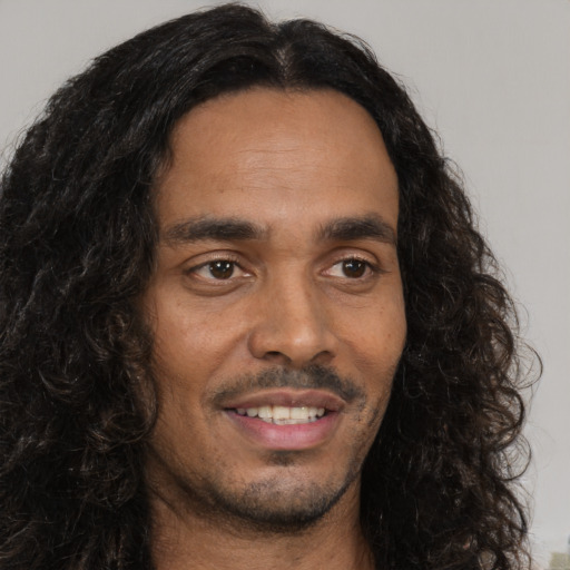 Joyful black young-adult male with long  brown hair and brown eyes