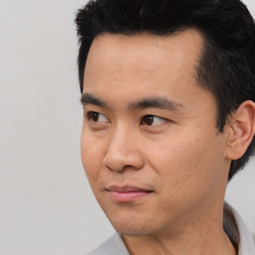 Joyful asian young-adult male with short  black hair and brown eyes