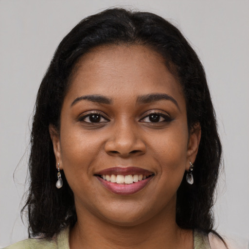 Joyful black young-adult female with long  brown hair and brown eyes