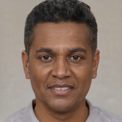 Joyful black adult male with short  black hair and brown eyes