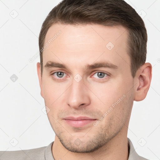 Joyful white young-adult male with short  brown hair and grey eyes