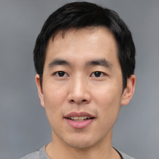 Joyful asian young-adult male with short  black hair and brown eyes