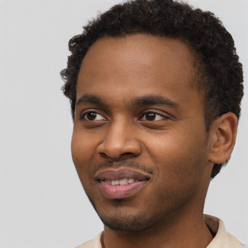 Joyful black young-adult male with short  brown hair and brown eyes