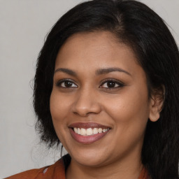 Joyful black young-adult female with long  brown hair and brown eyes