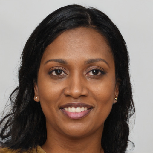 Joyful black young-adult female with long  brown hair and brown eyes