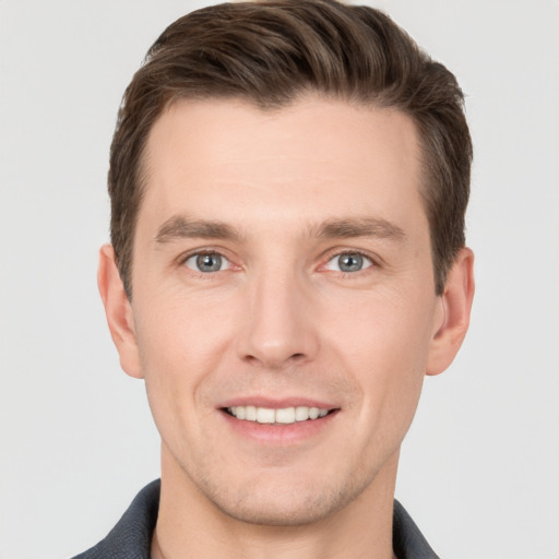 Joyful white young-adult male with short  brown hair and grey eyes