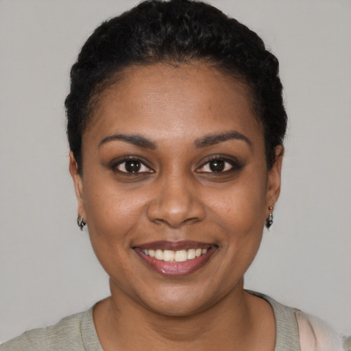 Joyful black young-adult female with short  black hair and brown eyes