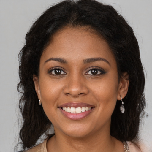 Joyful black young-adult female with long  brown hair and brown eyes