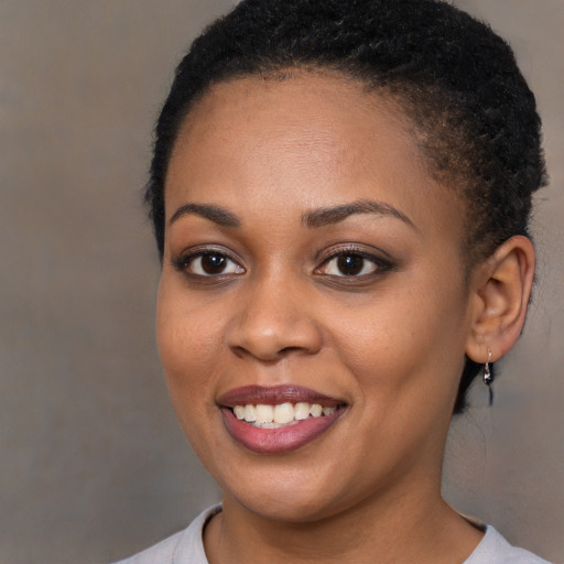 Joyful black young-adult female with short  brown hair and brown eyes