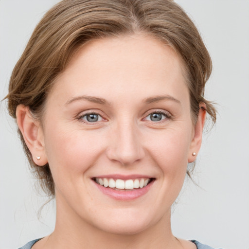 Joyful white young-adult female with medium  brown hair and grey eyes