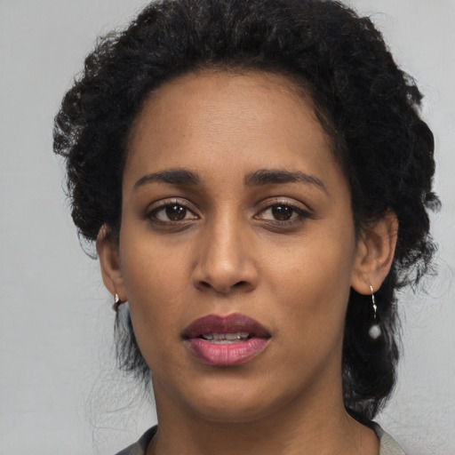 Joyful black young-adult female with short  black hair and brown eyes