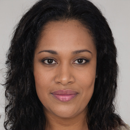 Joyful black young-adult female with long  brown hair and brown eyes