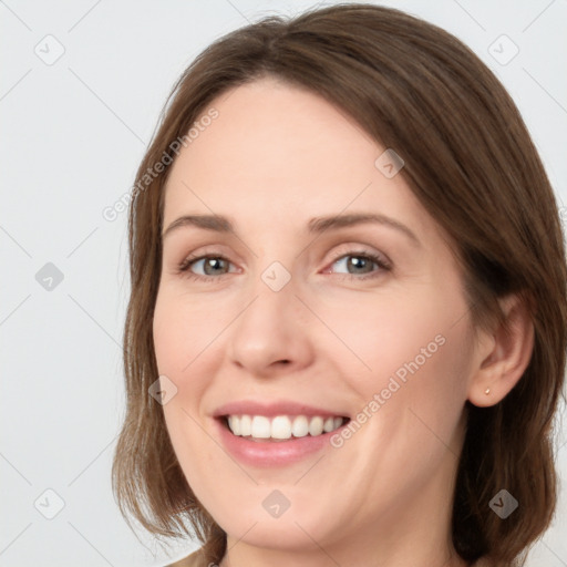 Joyful white young-adult female with medium  brown hair and grey eyes