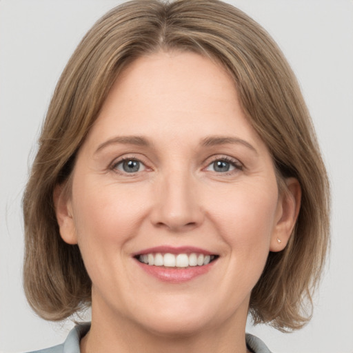 Joyful white adult female with medium  brown hair and grey eyes