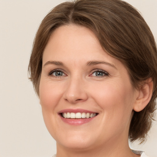 Joyful white young-adult female with medium  brown hair and green eyes