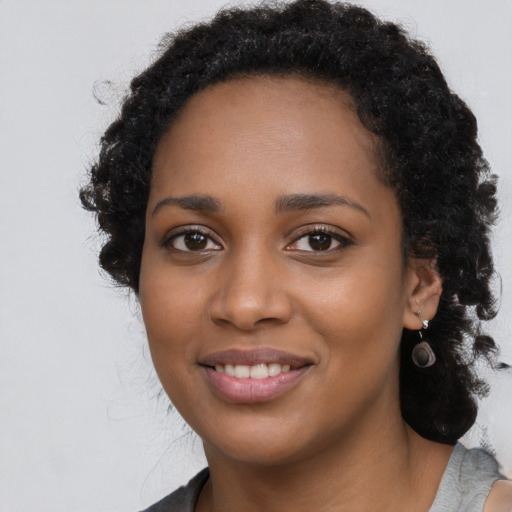 Joyful black young-adult female with long  black hair and brown eyes