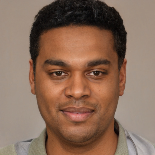 Joyful black young-adult male with short  black hair and brown eyes