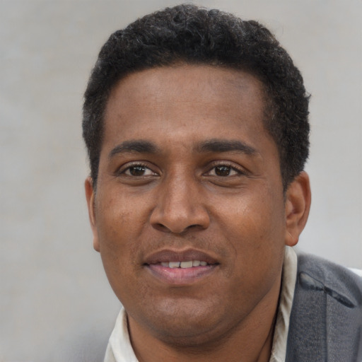 Joyful black young-adult male with short  brown hair and brown eyes