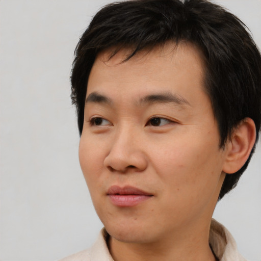 Joyful asian young-adult male with short  brown hair and brown eyes