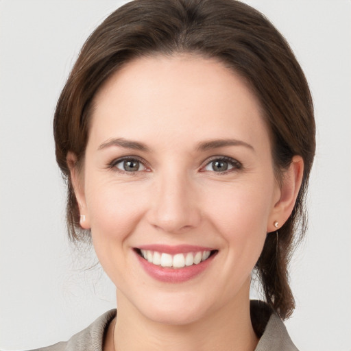 Joyful white young-adult female with medium  brown hair and grey eyes