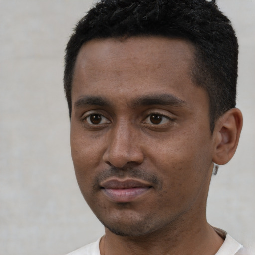 Joyful black young-adult male with short  black hair and brown eyes