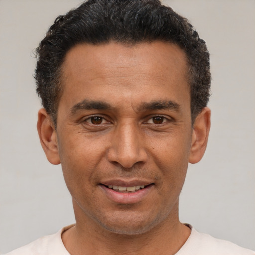 Joyful latino adult male with short  black hair and brown eyes