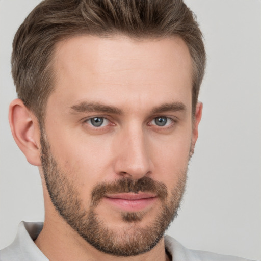 Joyful white young-adult male with short  brown hair and grey eyes