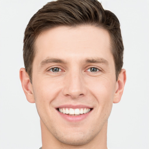 Joyful white young-adult male with short  brown hair and grey eyes