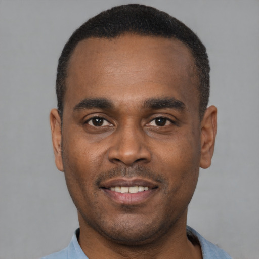 Joyful black young-adult male with short  black hair and brown eyes