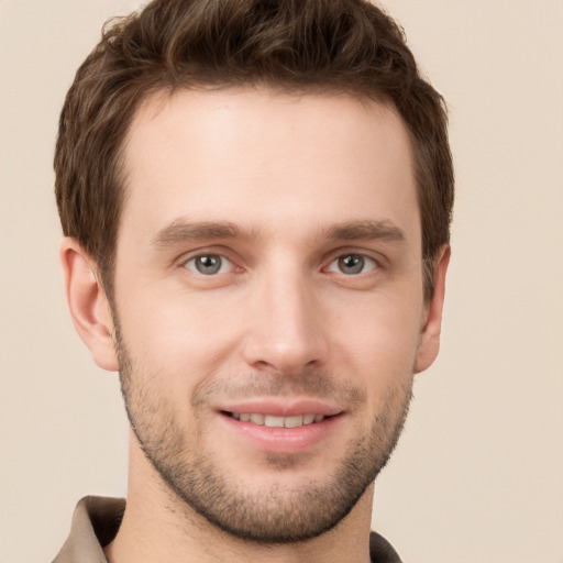 Joyful white young-adult male with short  brown hair and grey eyes