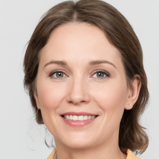 Joyful white young-adult female with medium  brown hair and grey eyes