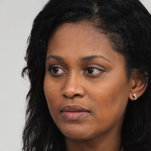 Joyful black young-adult female with long  black hair and brown eyes
