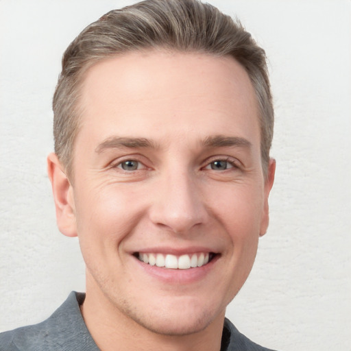 Joyful white young-adult male with short  brown hair and grey eyes