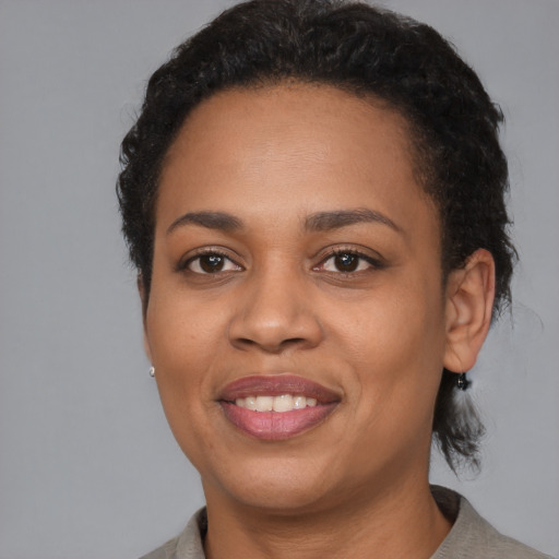 Joyful black young-adult female with short  black hair and brown eyes