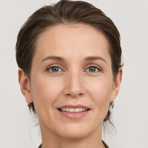 Joyful white young-adult female with medium  brown hair and grey eyes