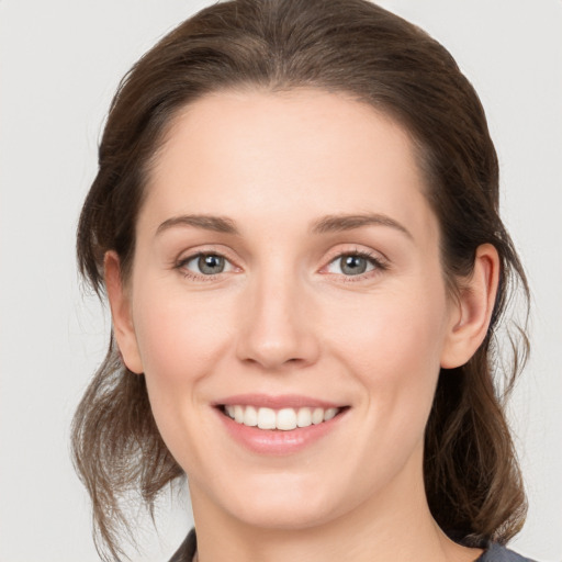 Joyful white young-adult female with medium  brown hair and grey eyes