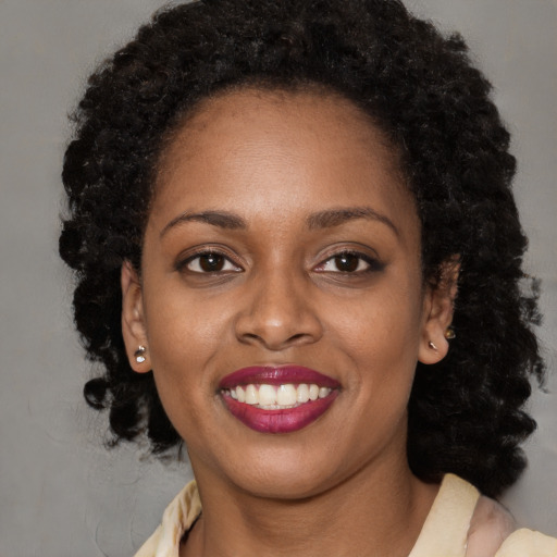 Joyful black young-adult female with long  brown hair and brown eyes