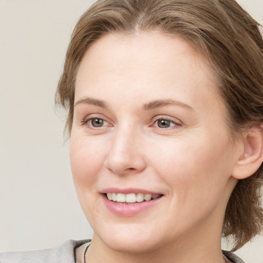 Joyful white young-adult female with medium  brown hair and grey eyes