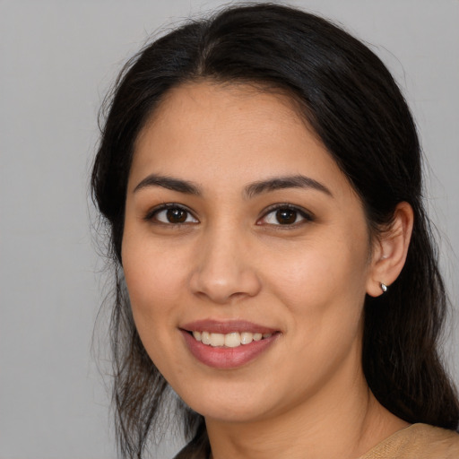 Joyful latino young-adult female with long  brown hair and brown eyes