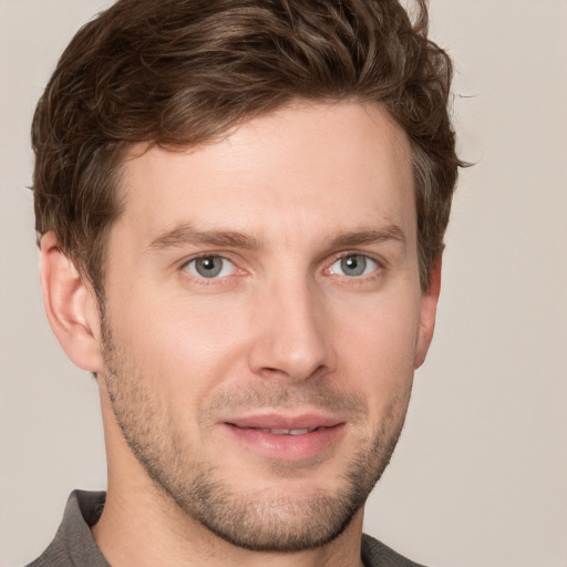 Joyful white young-adult male with short  brown hair and grey eyes