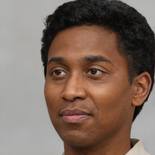 Joyful black young-adult male with short  black hair and brown eyes