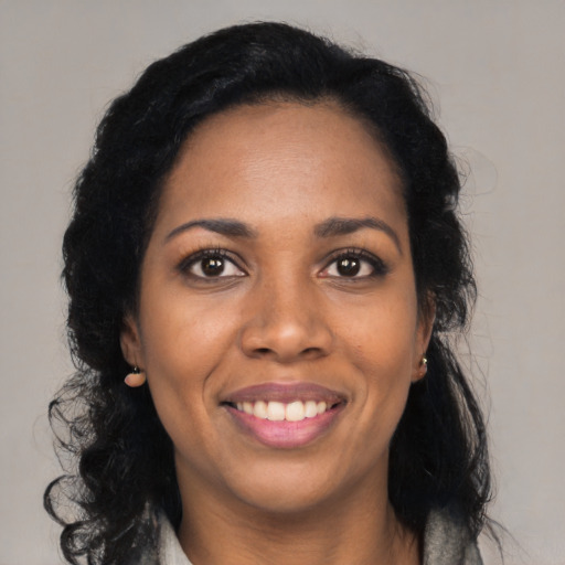 Joyful black young-adult female with long  black hair and brown eyes