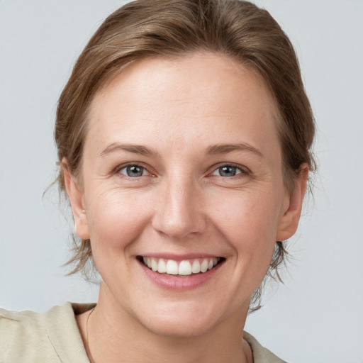 Joyful white young-adult female with medium  brown hair and grey eyes